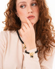 Bracciale con sfere in vetro nere e charms pendenti in metallo - Mya Accessories