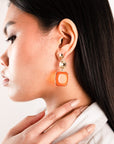 Orecchini in metallo pendenti in acrilico trasparente base quadrata arancio - Mya Accessories